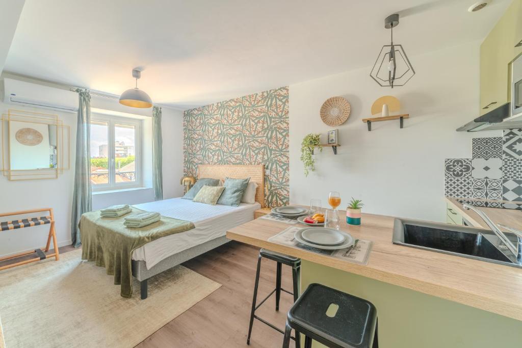 a room with a bed and a table and a kitchen at Hortensia Roanne centre-ville - Parking & Clim in Roanne