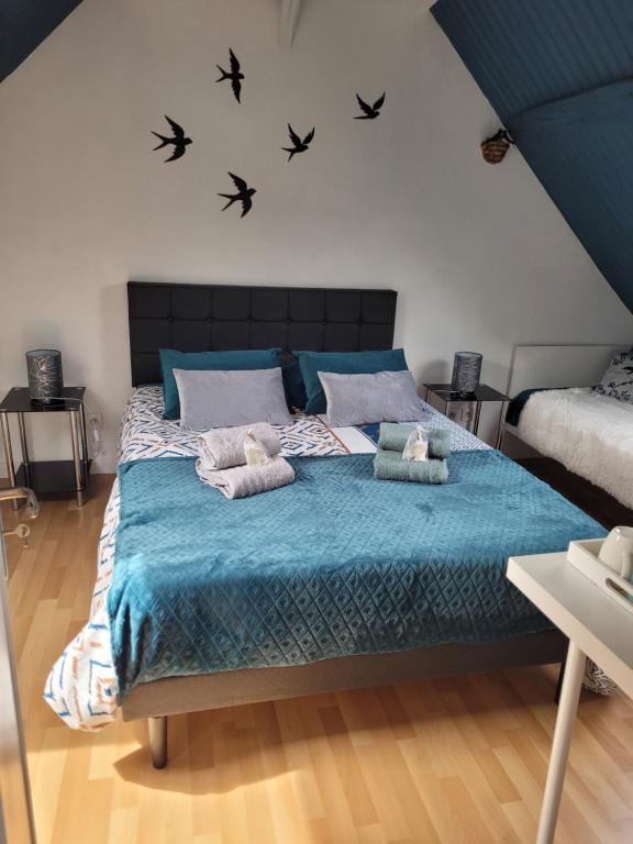 a bedroom with a large bed with birds on the wall at Les Hirondelles à 5 mn de l' aeroport in Beauvais