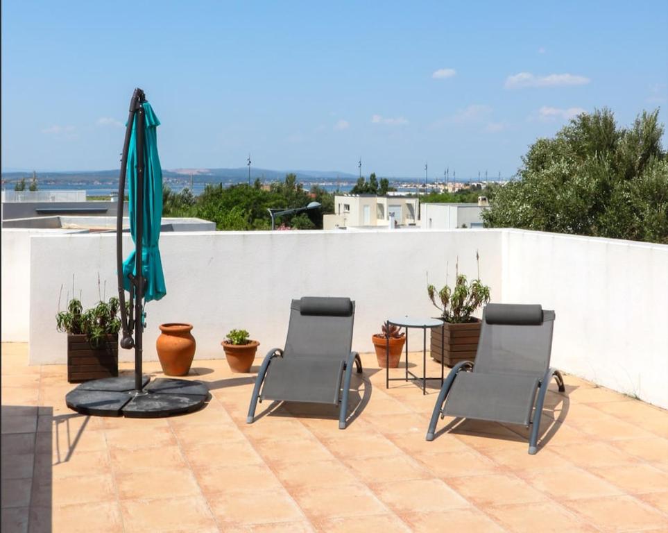 a patio with three chairs and a table and an umbrella at Villa Casa Bianca Beachfront Villeroy in Sète