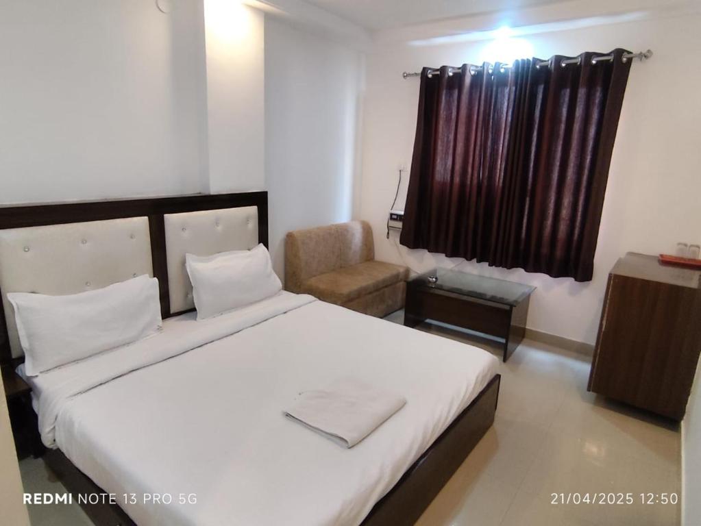 a bedroom with a large white bed and a chair at Hotel Navgrah Palace in Haridwār