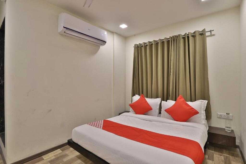 a bedroom with a bed with red pillows at Hotel O Ripple Mall in Surat