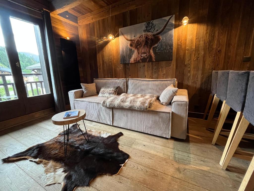 a living room with a couch and a bull painting at Appartement du Petit Bois in Megève
