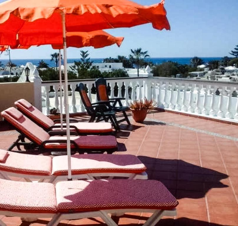 un grupo de sillas y una sombrilla en el balcón en Apartamento Sole mit Meerblick, en Puerto del Carmen