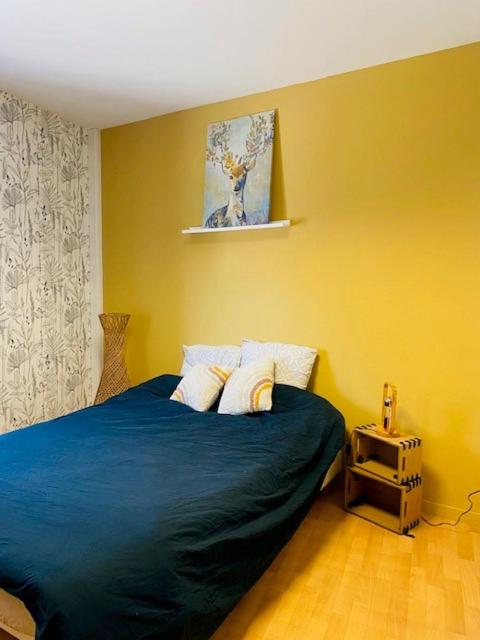 a bedroom with a blue bed with yellow walls at Popote et Papote-L'escale Pro in Saint-Thurial