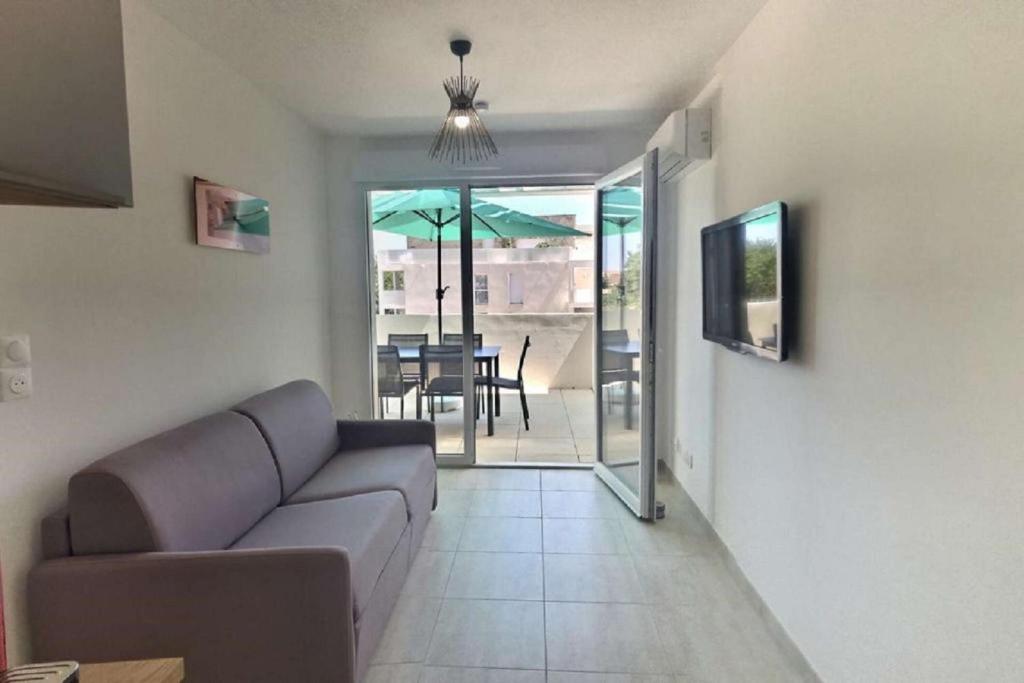 a living room with a couch and a table with an umbrella at Bel appartement Valras-Plage in Sérignan