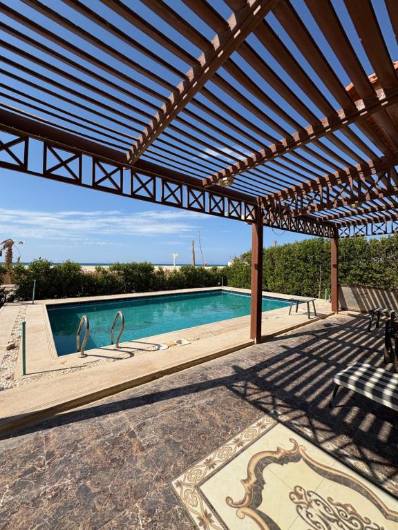 a swimming pool with two swan statues under a pergola at Coronado Dabaa Beach in Zāwiyat ‘Abd al Mun‘im