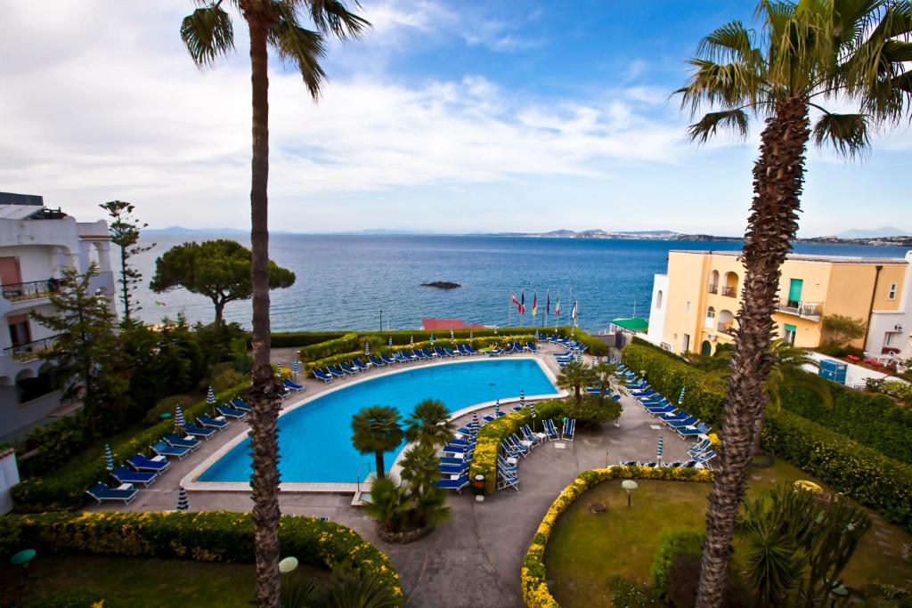 widok na basen z palmami i ocean w obiekcie Hotel Terme Alexander w mieście Ischia