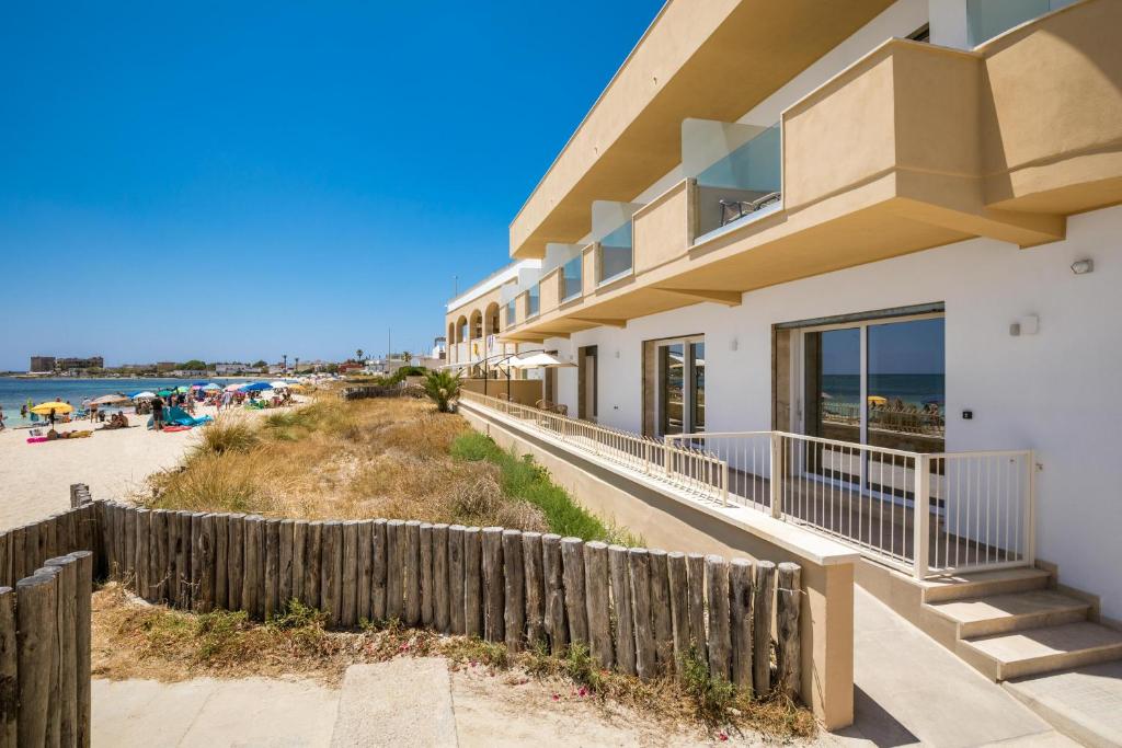a house with a fence next to the beach at Nella Suites in Torre Lapillo