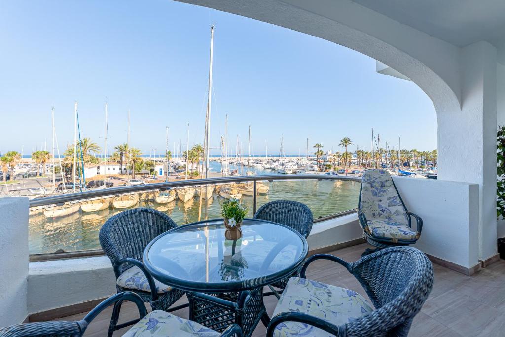 a table and chairs on a balcony with a marina at Holiday Rental apartment with Panoramic Terrace Views of Puerto Marina Island in Benalmadena Costa