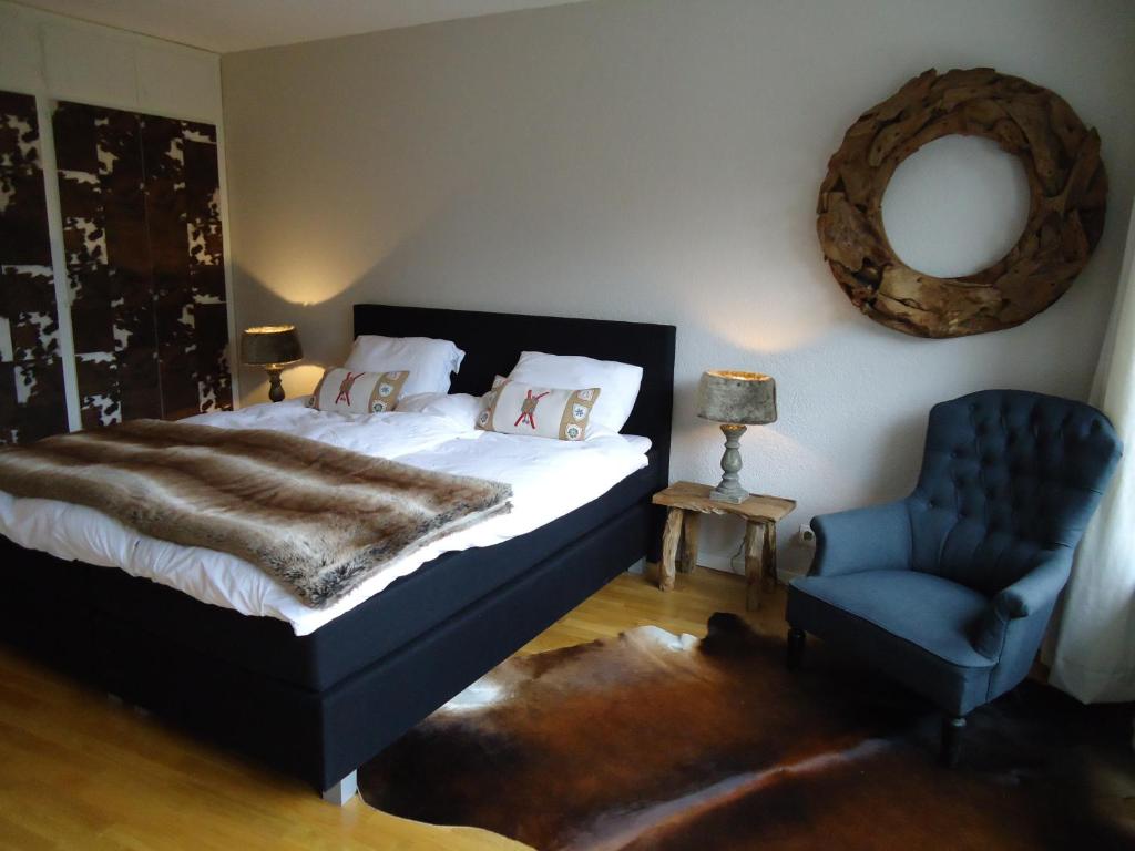 1 dormitorio con 1 cama y 1 silla azul en Apartment Humagne - Crans-Montana Center, en Crans-Montana