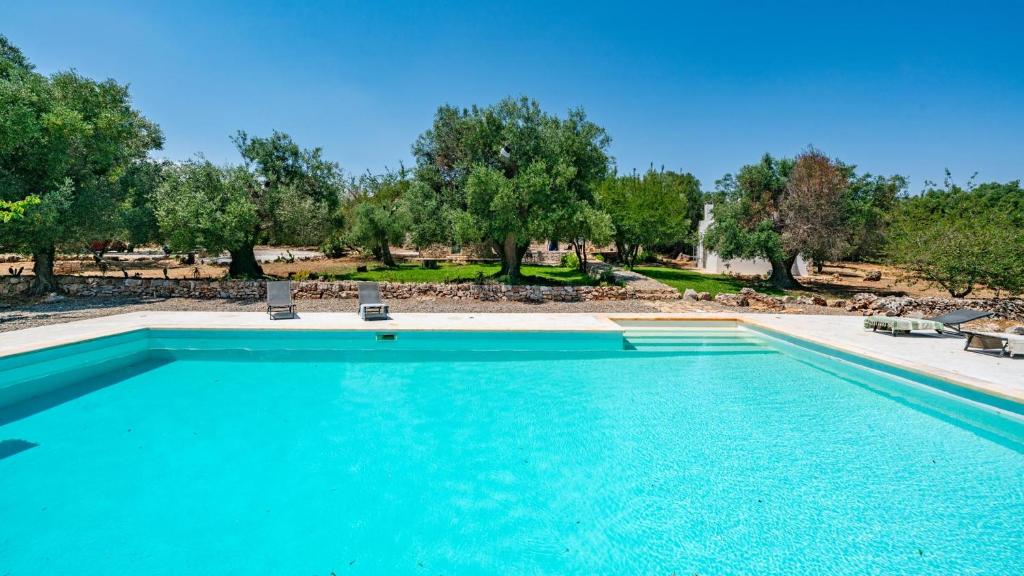a swimming pool with two chairs and trees at Casa di Paolo by Rentbeat in Ceglie Messapica