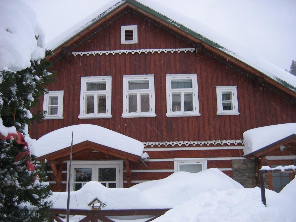una casa roja con nieve en el techo en Horský dům, en Pec pod Sněžkou