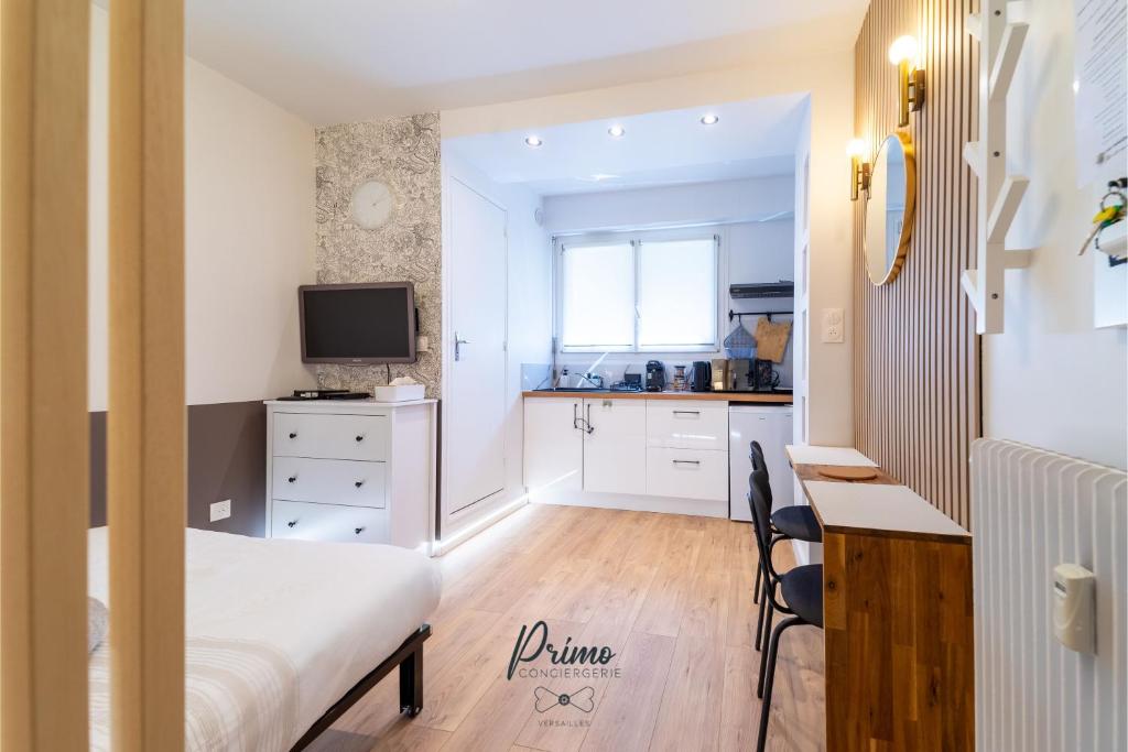 ein Schlafzimmer mit Bett und Schreibtisch und eine Küche in der Unterkunft l'Atypique Calme, Proche Gare & Centre ville in Versailles