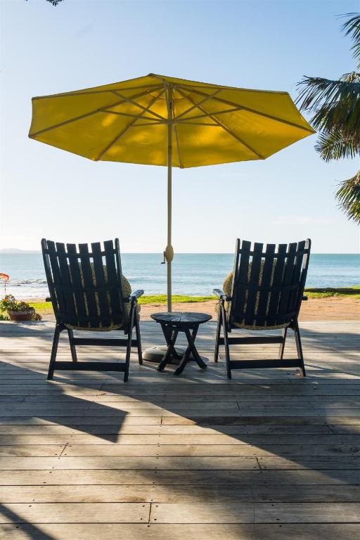 two chairs and an umbrella on the beach at Driftwood Lodge Beachfront, Cable Bay Stays, Cable Bay, Northland in Coopers Beach