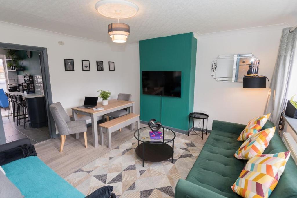 un salon avec un canapé vert et une table dans l'établissement 4 Bedroom cosy home Birmingham, à Birmingham