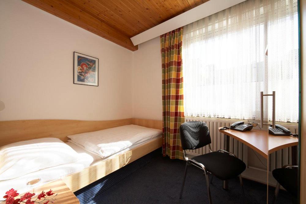 a bedroom with a bed and a desk and a window at Hotel Erbprinzenhof in Karlsruhe