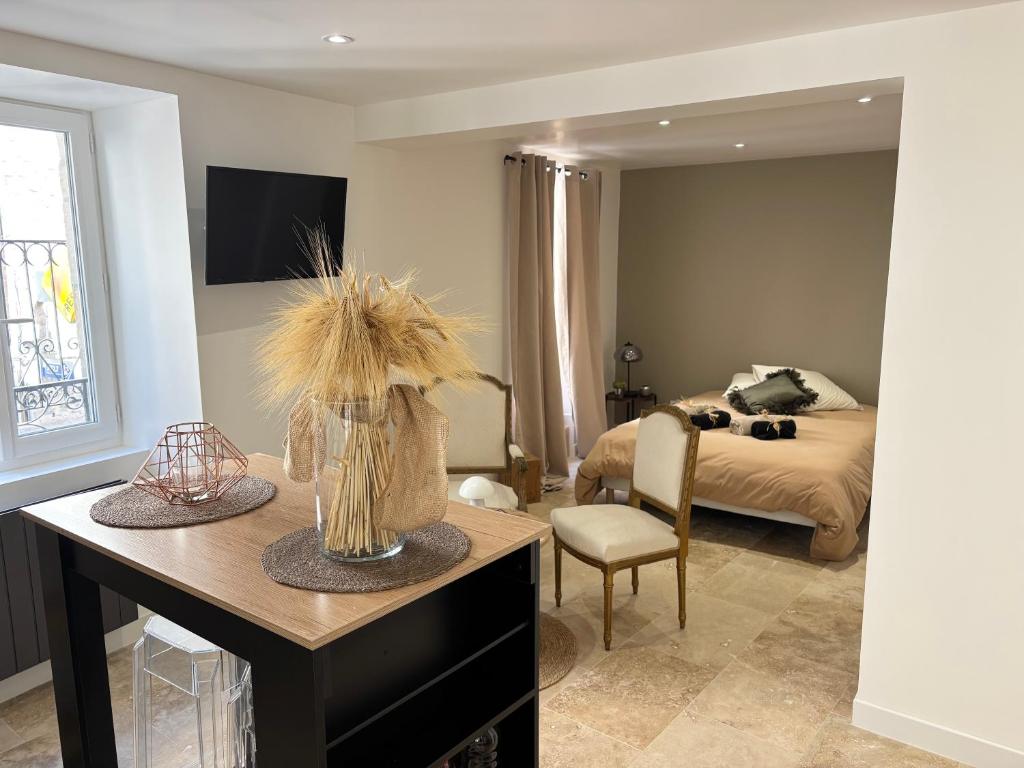 ein Schlafzimmer mit einem Bett und einem Tisch mit einer Vase mit Gras in der Unterkunft Chaleureux T1 avec Balcon in Vals-les-Bains