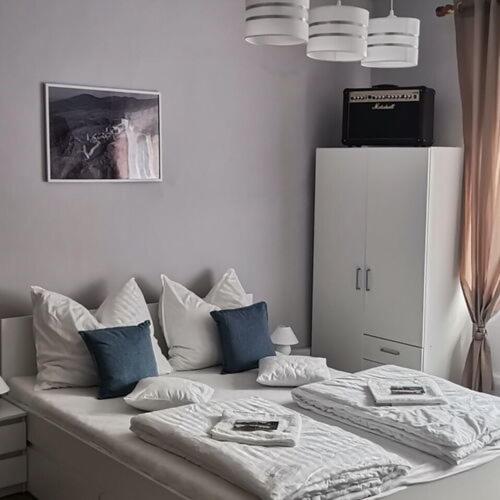 een wit bed met blauwe kussens in een slaapkamer bij Szökőkút vendégszállás in Sátoraljaújhely
