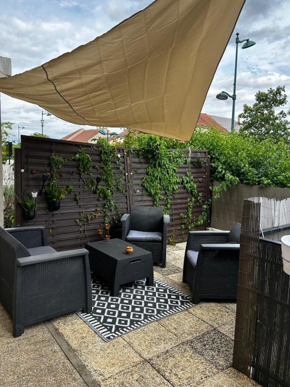 un patio avec des chaises, une table et un parasol dans l'établissement Appartement 2 pièces terrasse Magny le Hongre, à Magny-le-Hongre