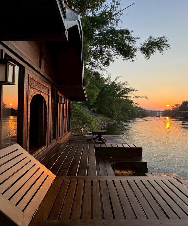 a wooden deck with a picnic table next to the water at Kawarin River Exclusive Hotel & Resort in Ban Gaeng Cho