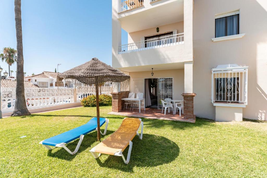 a house with a lawn with two chairs and an umbrella at La Riviera in La Cala de Mijas