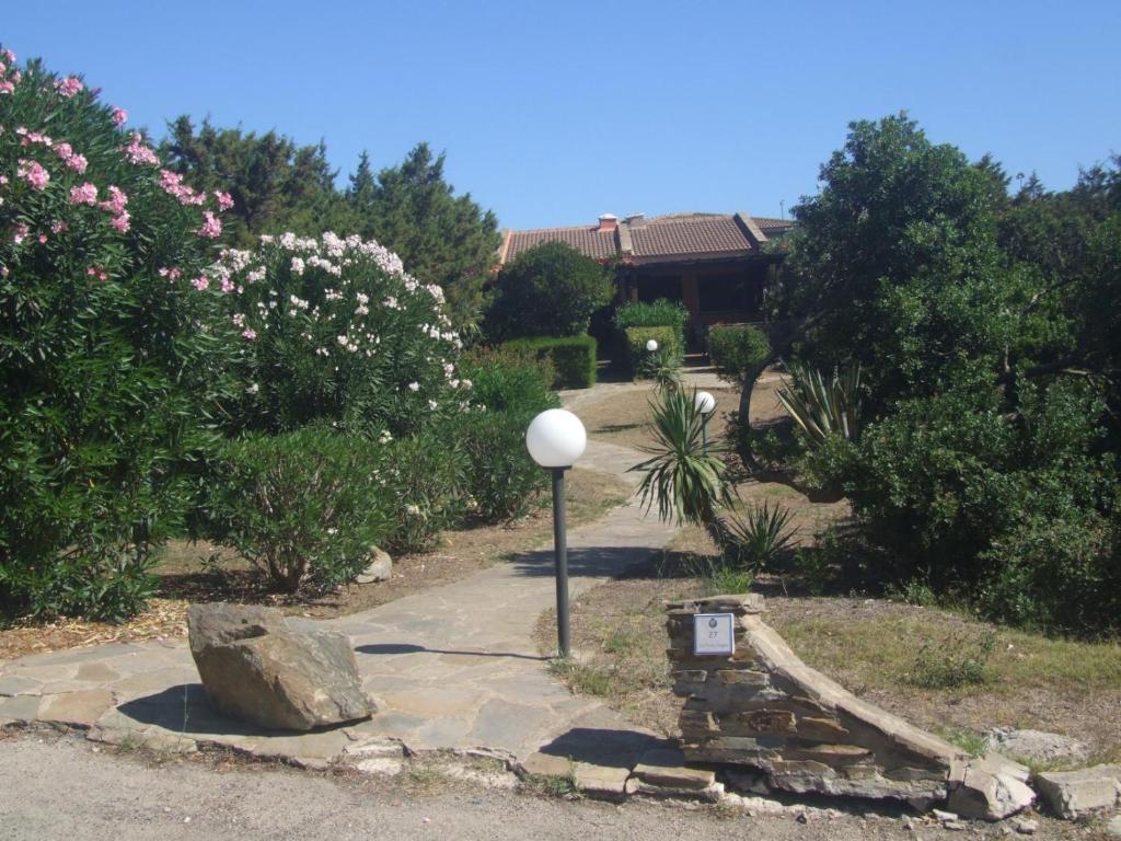 a street light in a garden with a rock and flowers at Villa Delogu in Stintino