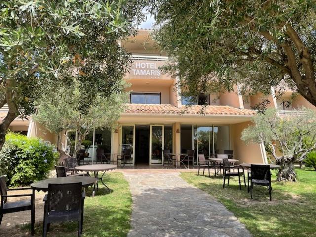 a hotel with tables and chairs in front of a building at Hôtel Tamaris in Le Lavandou