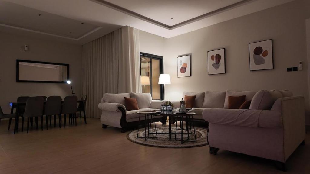 a living room with a couch and a table and chairs at كمباوند ماربيلا الكورنيش شقة in Ar Rākah