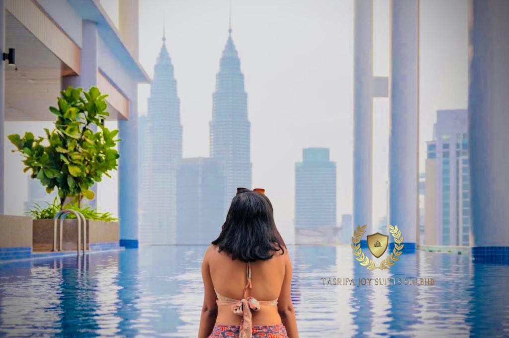 a woman in a bikini standing in the water in a city at The Majestic Gen Luxury Suites KLCC in Kuala Lumpur