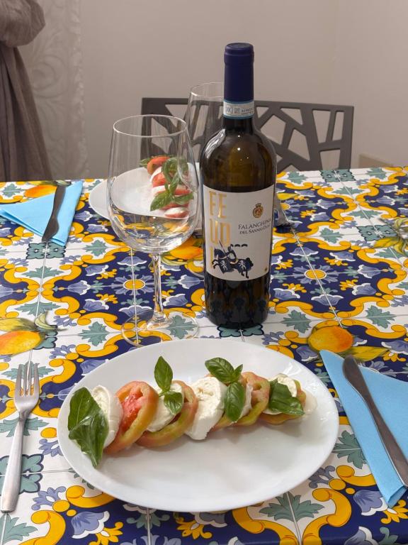 a plate of food on a table with a bottle of wine at Rosso Napoli locazioni brevi in Naples