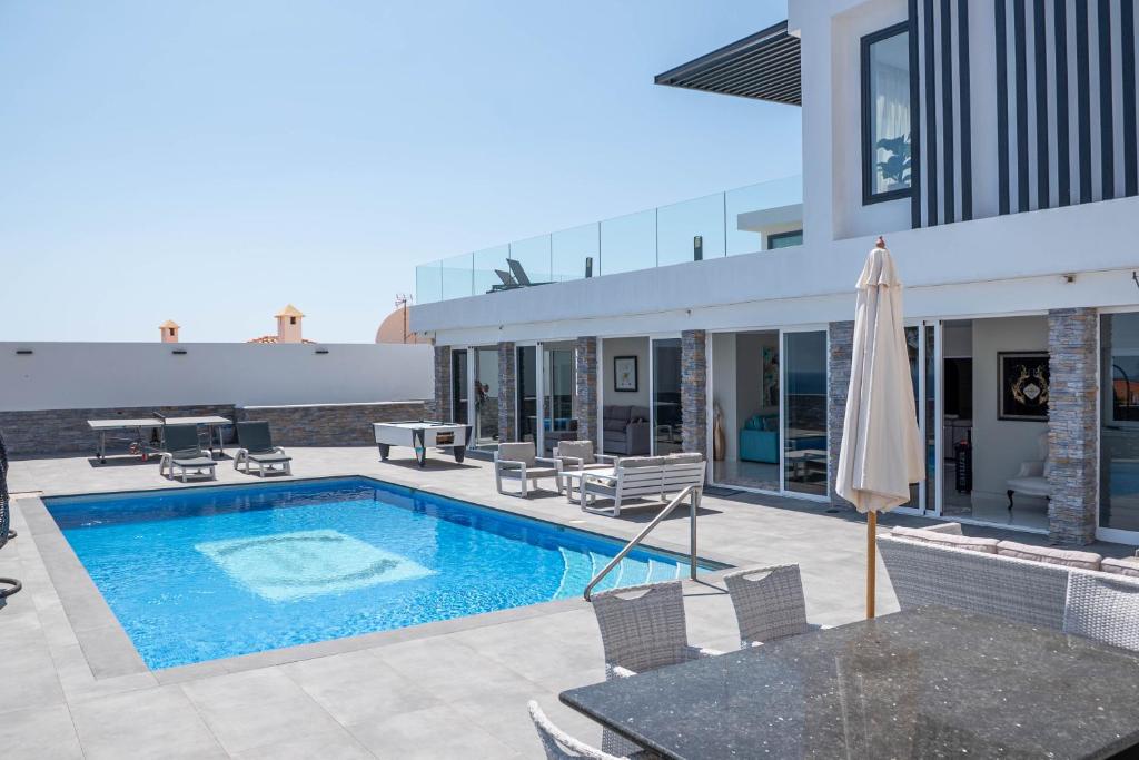 a pool with chairs and an umbrella next to a building at Villa El Padrino in Callao Salvaje