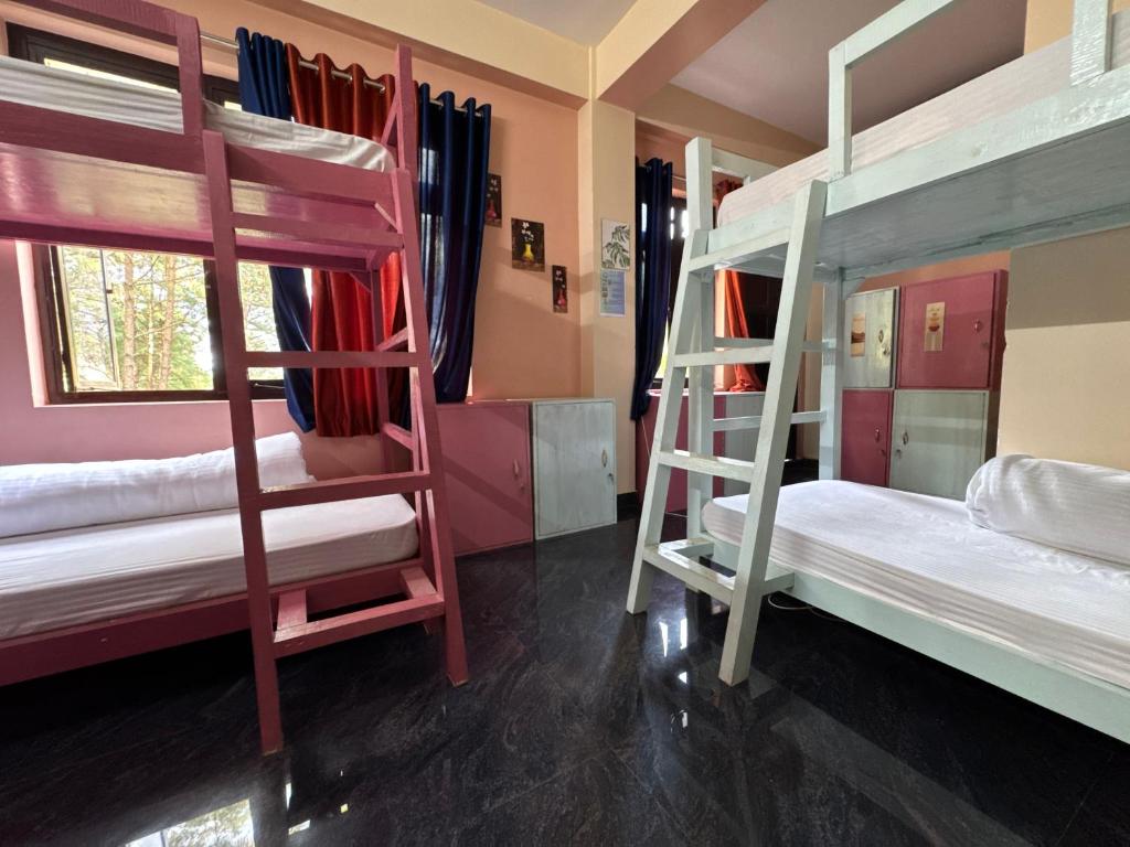 a room with three bunk beds in a room at XTSY Travellers Hostel in Shillong