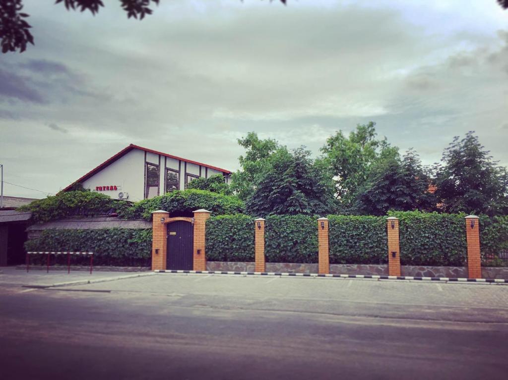a fence in front of a building with a hedge at Nakhodka Inn in Mykolaiv