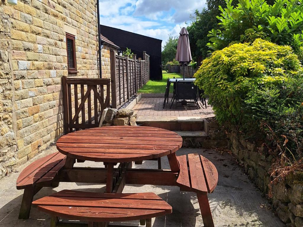a wooden table and bench next to a brick building at Boundcliffe Farm in Allerston
