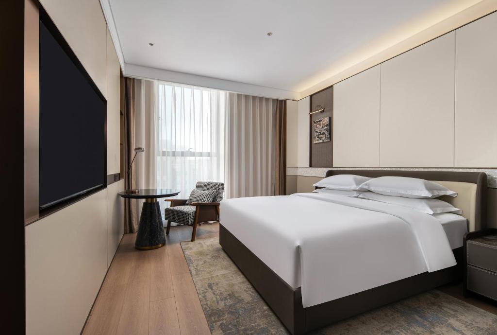 a bedroom with a white bed and a tv at Wyndham Garden Urumqi Innovation Square in Ürümqi