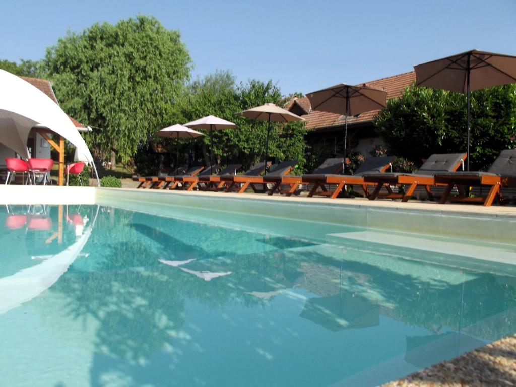 a swimming pool with tables and umbrellas and chairs at Remser Haus in Zalakaros