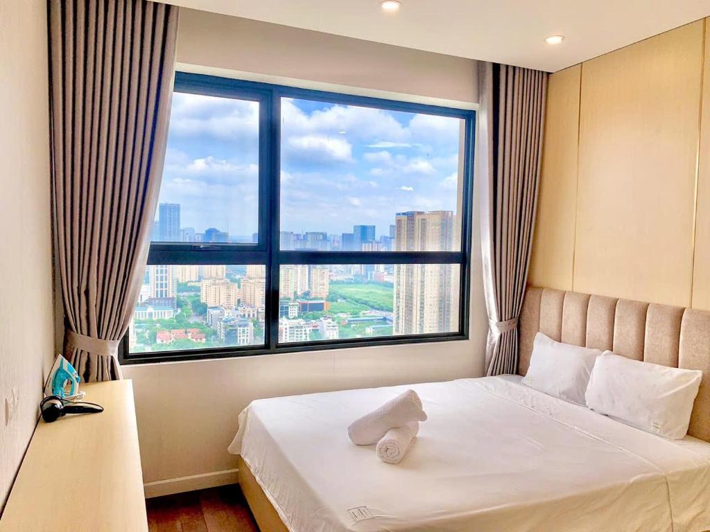 a bed in a room with a large window at Vinhomes D'Capitale - Luka homes in Hanoi