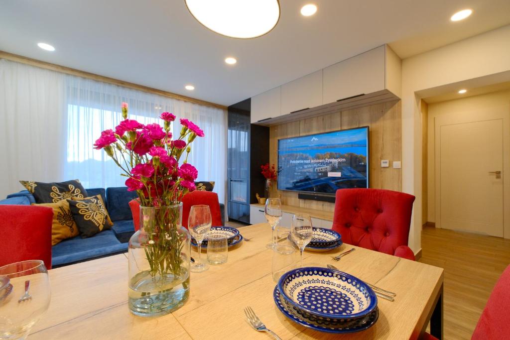 a dining room table with a vase of flowers on it at Laguna Beskidów Resort - Apartament Podhalański in Zarzecze