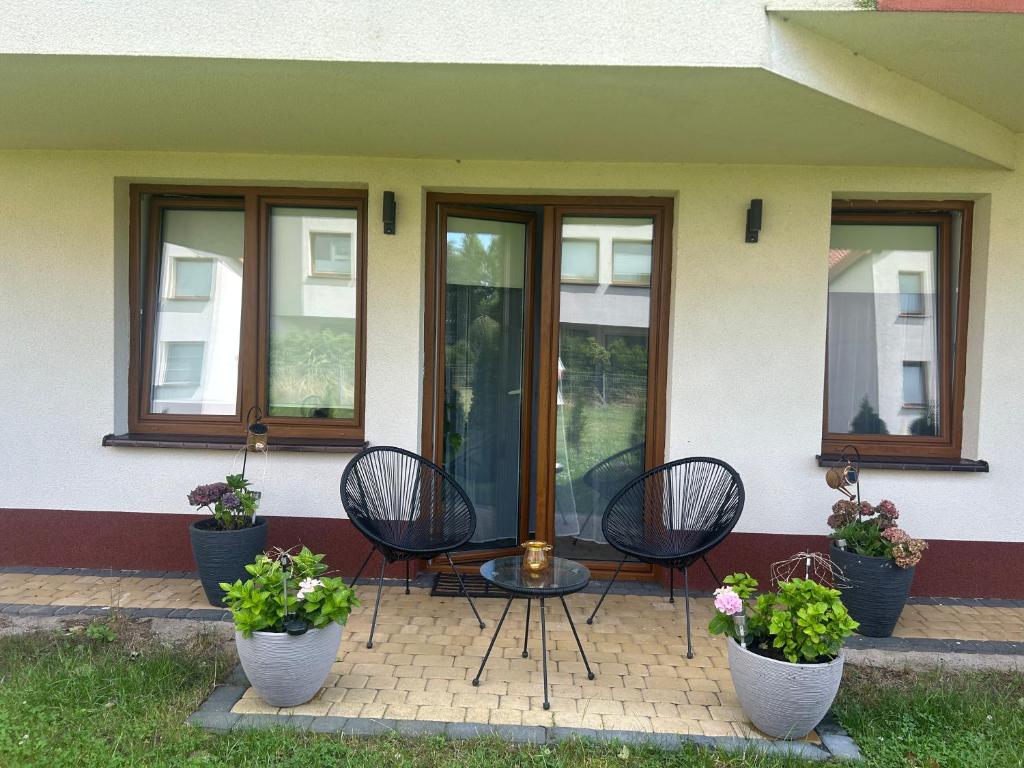 a patio with three chairs and a table with flowers at APARTAMENT OFELIA in Darłówko