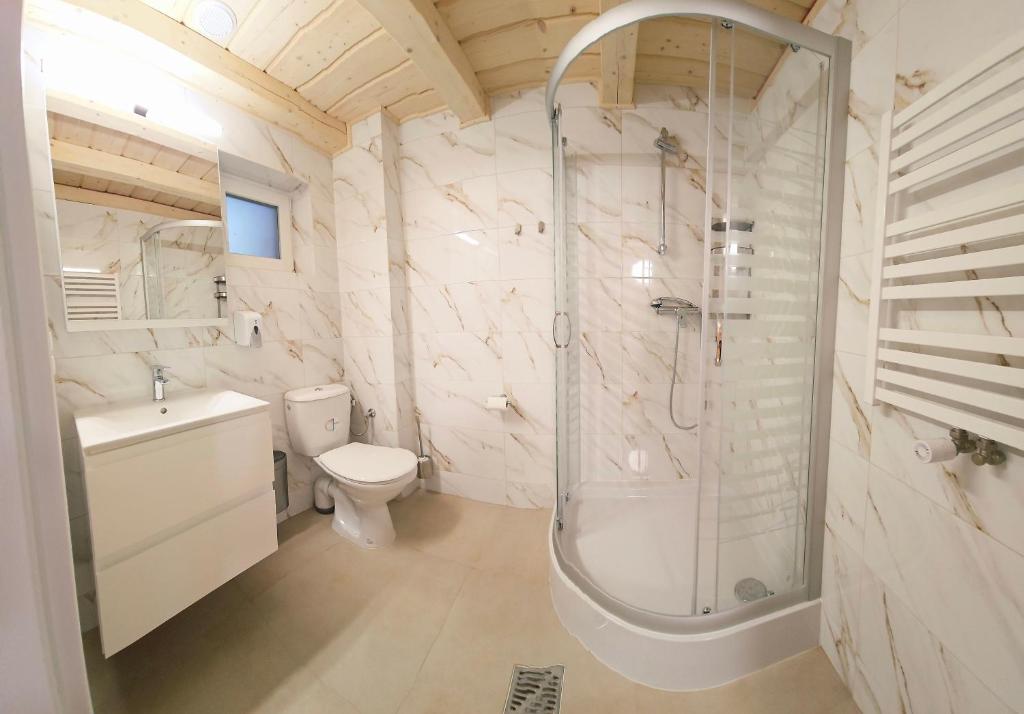 Modern bathroom with marble walls, shower cabin, and wooden ceiling.