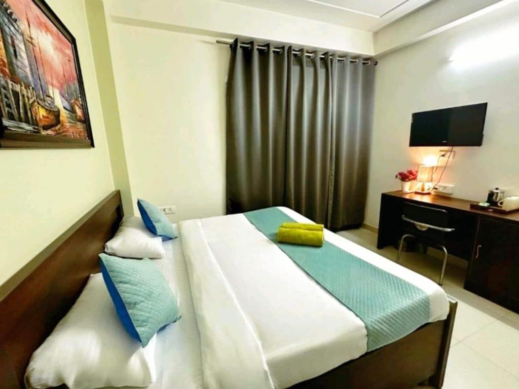 a bedroom with a bed with a desk and a television at HOTEL O THE VIRAAT in Noida