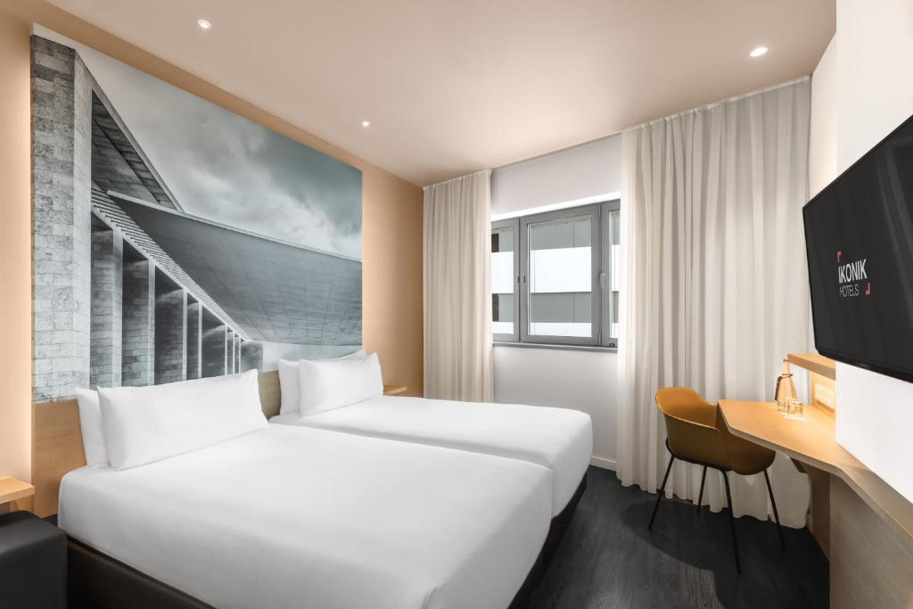 A twin room with two separate beds, a desk, and a small window beneath a large architectural mural.