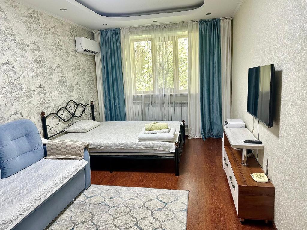 una camera con 2 letti, una TV e un divano di Апартаменты аэропорт a Almaty