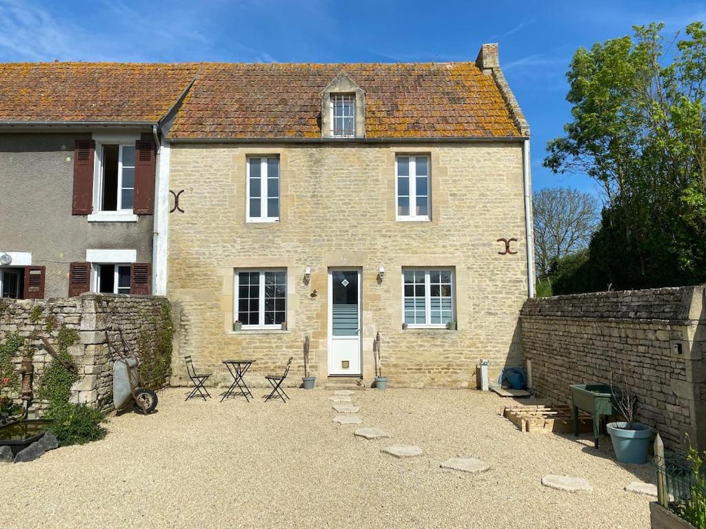ein Backsteinhaus mit Stühlen und Tischen davor in der Unterkunft Petite maison de campagne in Sainte-Croix-sur-Mer