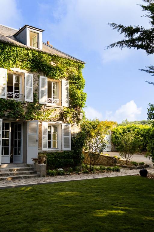 une maison blanche avec du lierre vert dans l'établissement Le Domaine by A&G - Vendrest, à Vendrest