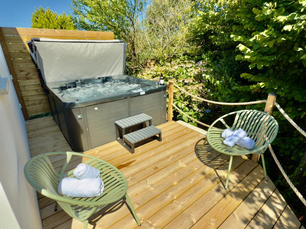 a deck with two chairs and a hot tub at Maison des Chênes 64 - Spa Lodge in Boucau