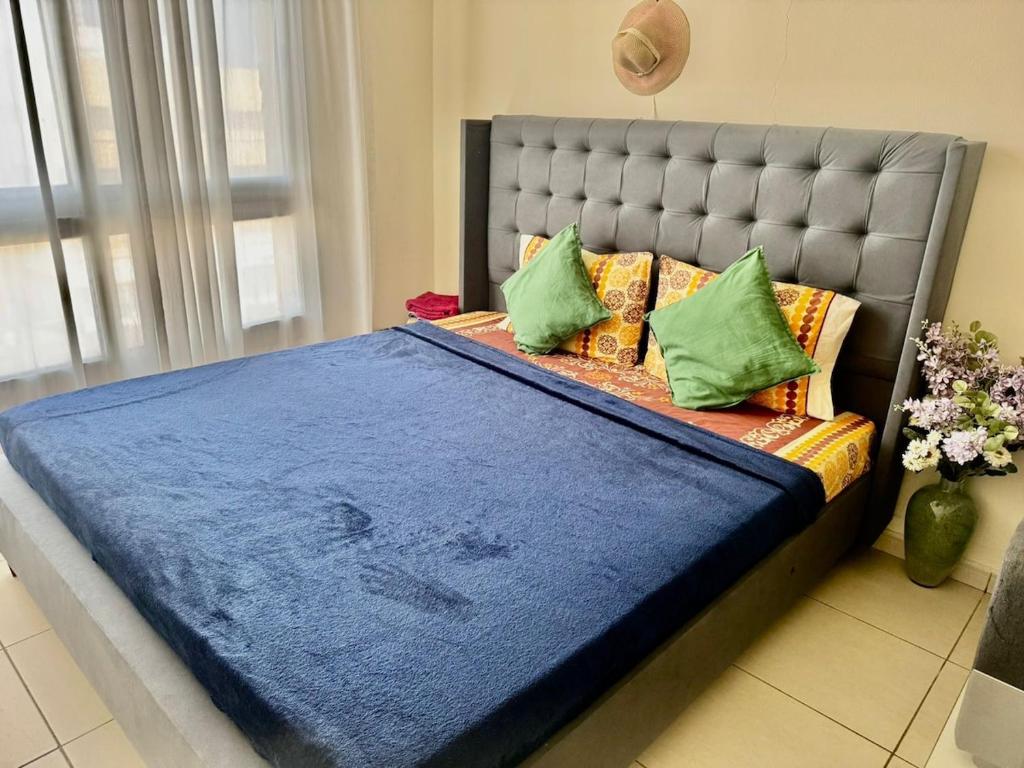 a bed with a blue blanket and green pillows at Not far from metro and WTC in Dubai