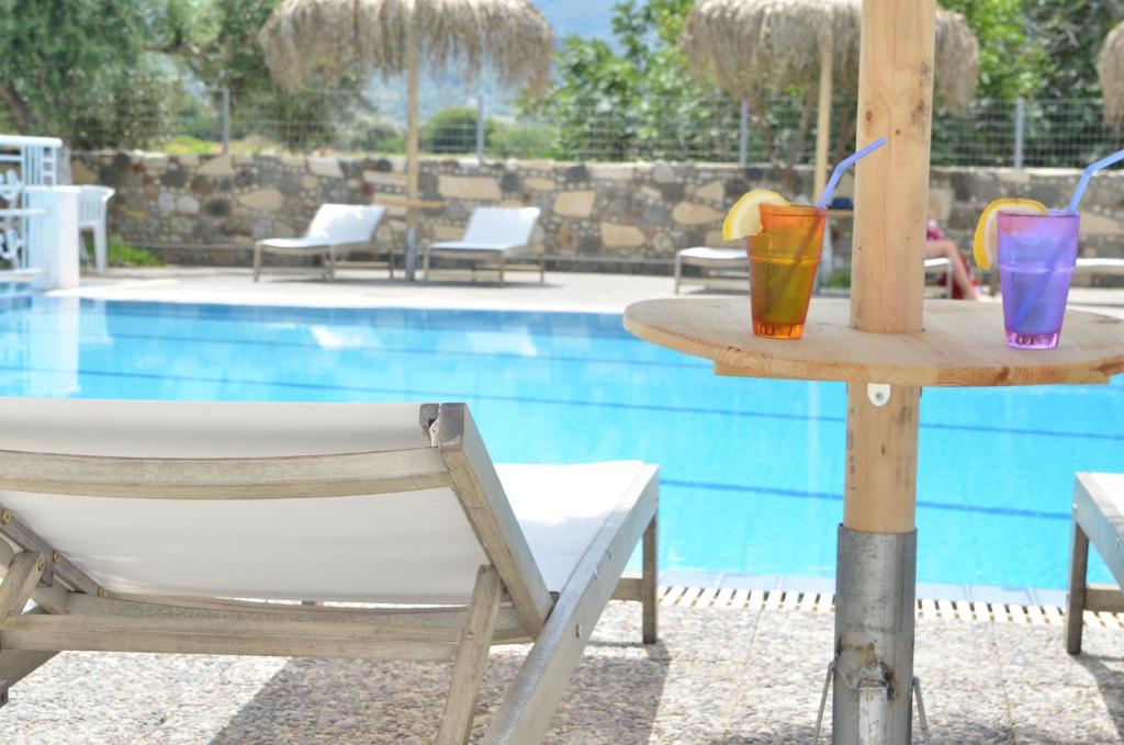 a table with two drinks on it next to a pool at Blue Nest Hotel in Tigaki