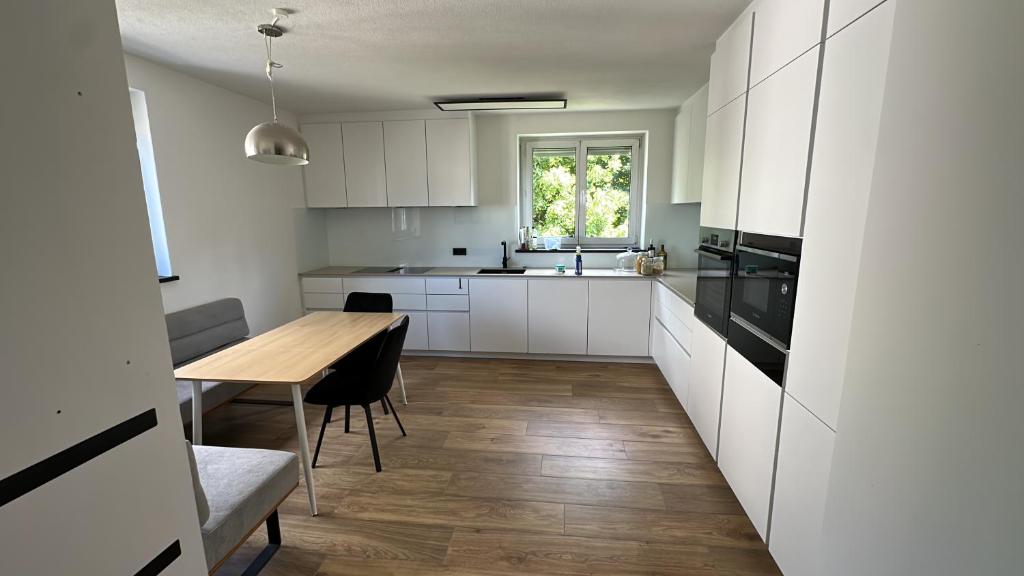 a kitchen with white cabinets and a wooden table at SeeZeit Friedrichshafen in Friedrichshafen