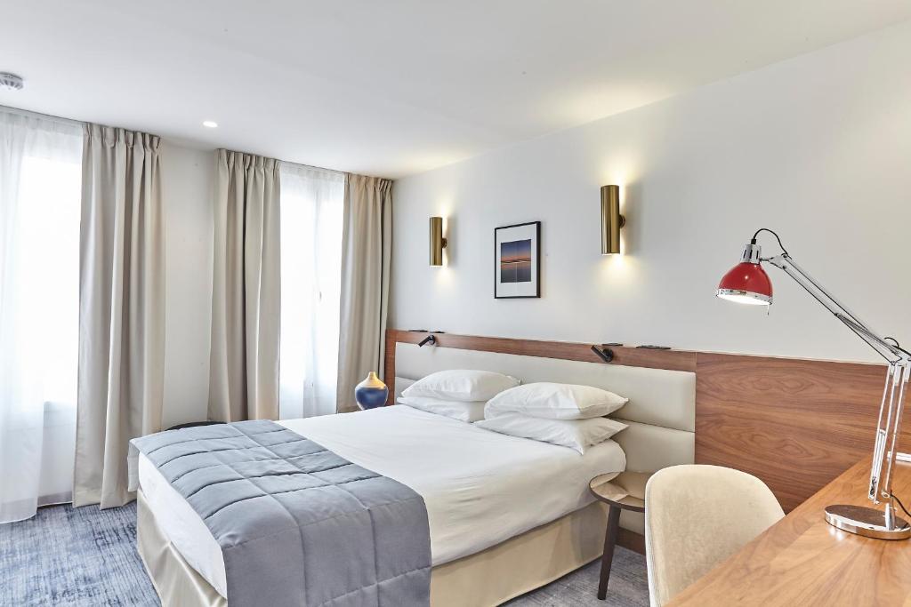 パリにあるホテル ロイヤル ファルのベッドとデスクが備わるホテルルームです。
